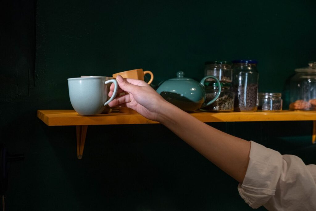 棚から器を取る手元。高い位置は取り出す動作が増える